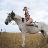 A young playful teen girl posing nude with her horse