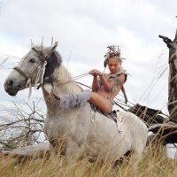 A young playful teen girl posing nude with her horse